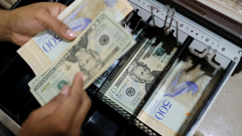 Купюры в размере 20 долларов США были замечены в кассе булочной в Каракасе, Венесуэла, 26 июня 2019 года. Венесуэльцы обратились к доллару США для оплаты повседневных покупок, поскольку их собственная валюта, боливар, обесценилась на 95 процентов.