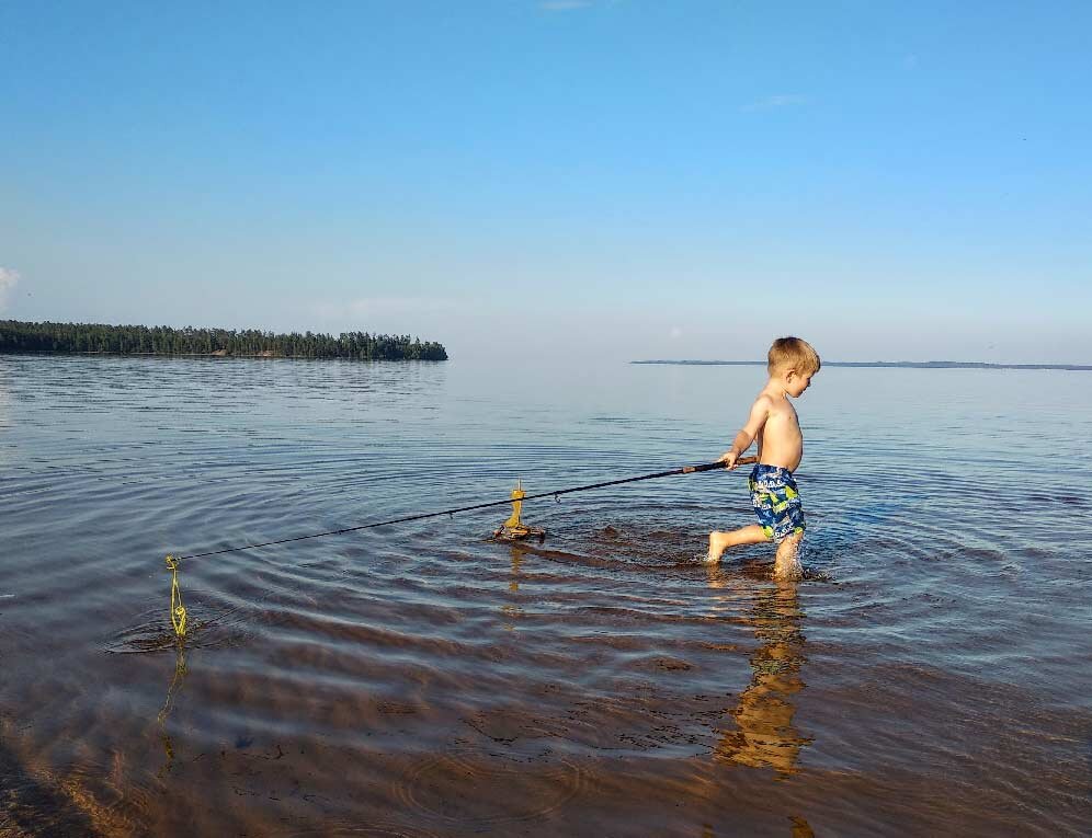 Фото автора: сын на Ладоге, катает удочкой кораблик, сделанный дедушкой.