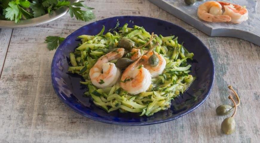 ИНГРЕДИЕНТЫ 500 г крупных креветок
5–6 средних цукини
2 зубчика чеснока
250 мл куриного или овощного бульона
100 мл белого вина
3 ст. л. лимонного сока
2 ст. л. каперсов
5 веточек петрушки
оливковое масло
соль, свежемолотый черный перец
ПОШАГОВЫЙ РЕЦЕПТ ПРИГОТОВЛЕНИЯ
Шаг 1
Заранее разморозьте креветки, если используете замороженные. Очистите их от панцирей, при желании оставьте хвостики. Надрежьте креветки вдоль по спинке, удалите темную кишечную вену. Сполосните холодной водой и обсушите бумажными полотенцами.
Шаг 2
Нарежьте цукини тонкой длинной соломкой. Положите в дуршлаг и немного посолите. Оставьте на 15 мин., а затем аккуратно отожмите, чтобы удалить лишнюю жидкость.
Шаг 3
Очистите чеснок и мелко порубите. Разогрейте 2 ст. л. оливкового масла на сковороде и обжарьте чеснок в течение 30 сек. Добавьте креветки и жарьте, помешивая, 1 мин. Влейте вино и дождитесь, пока оно закипит.
Шаг 4
Смешайте в небольшой миске крахмал с бульоном и вылейте в сковороду вместе с лимонным соком. Добавьте каперсы и продолжайте готовить 4–5 мин. на медленном огне, пока соус слегка не загус­теет.
Шаг 5
В другой сковороде разогрейте 1 ст. л. оливкового масла на среднем огне. Добавьте цукини и жарьте, аккуратно помешивая, 5 мин., в конце приготовления поперчите.
Шаг 6
Переложите цукини на блюдо, сверху выложите креветки с соусом и посыпьте мелко нарезанной петрушкой.
