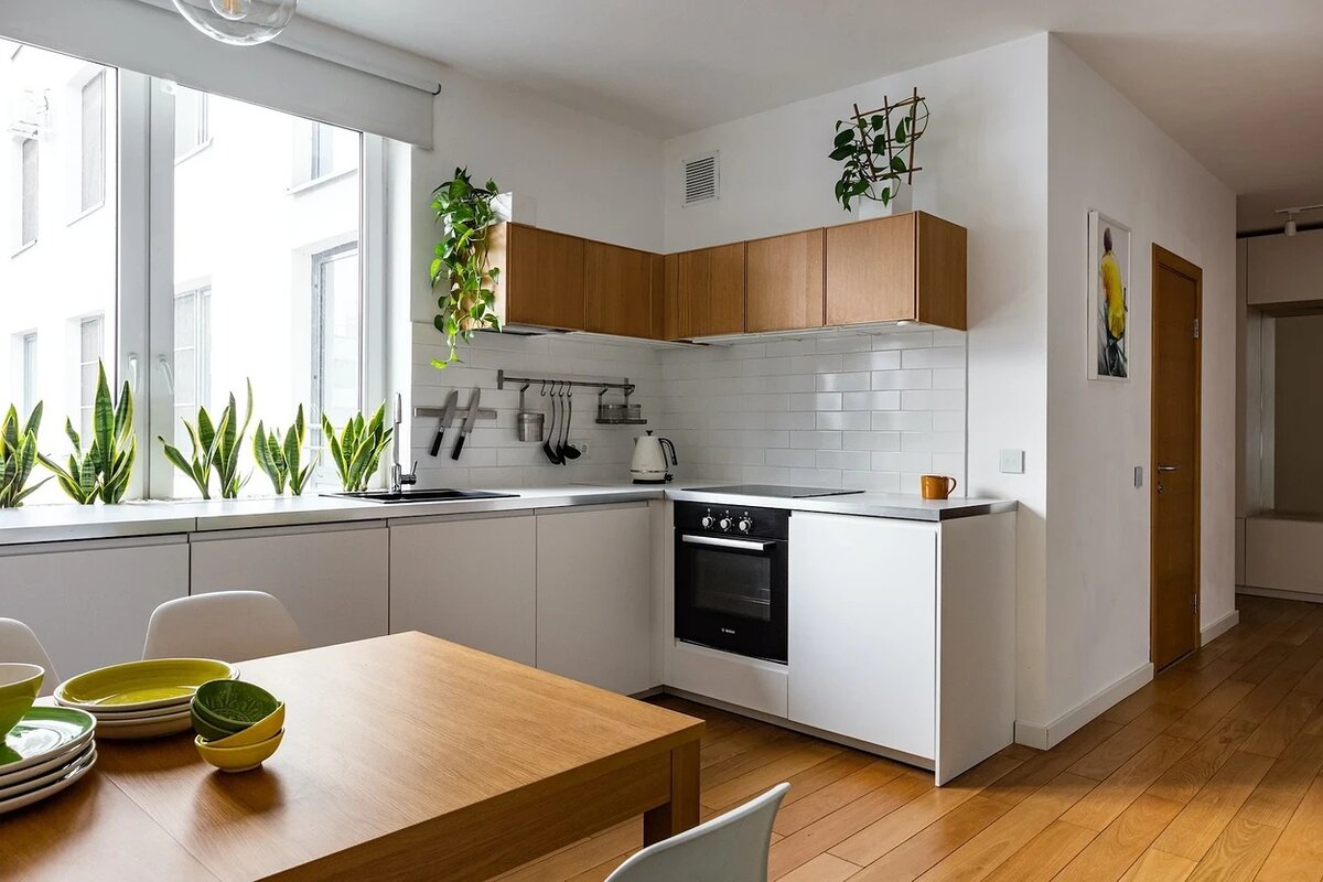 На границе кухни и гостиной расположили столовую группу. Обеденный стол освещают три подвеса со стеклянными плафонами.