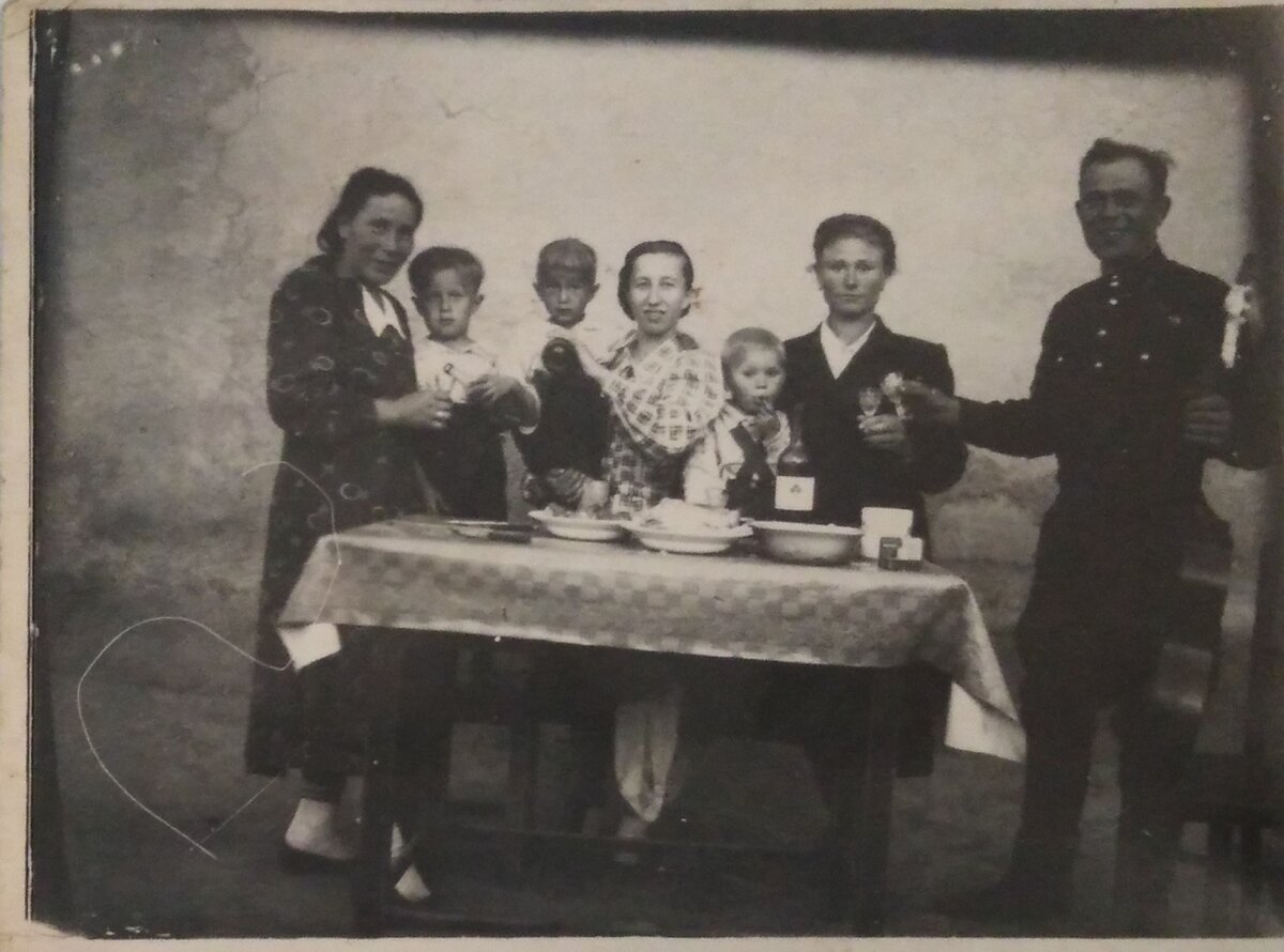 Фото из семейного  архива. По краям стола семейная пара карачаевцев, желавшая усыновить ребенка с нашей семьи,  За женщиной Толик,  за ним мать с Витей на руках, Володя со своей мамой Кристиной.