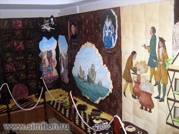 Стены сплошь выложены черным и белым шоколадом. Картины нарисованы на шоколадной плите пищевыми красками. Внизу стены полочка так же выложена шоколадом. Шоколадные чашки на шоколадном подносе.