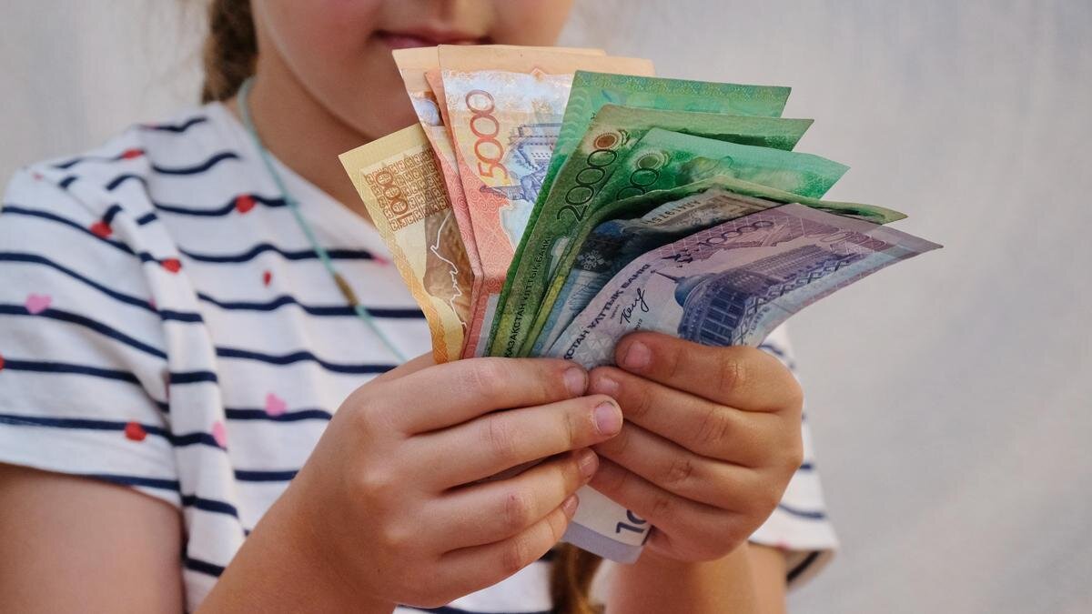    Девочка держит в руках купюры тенге:NUR.KZ/Владимир Третьяков