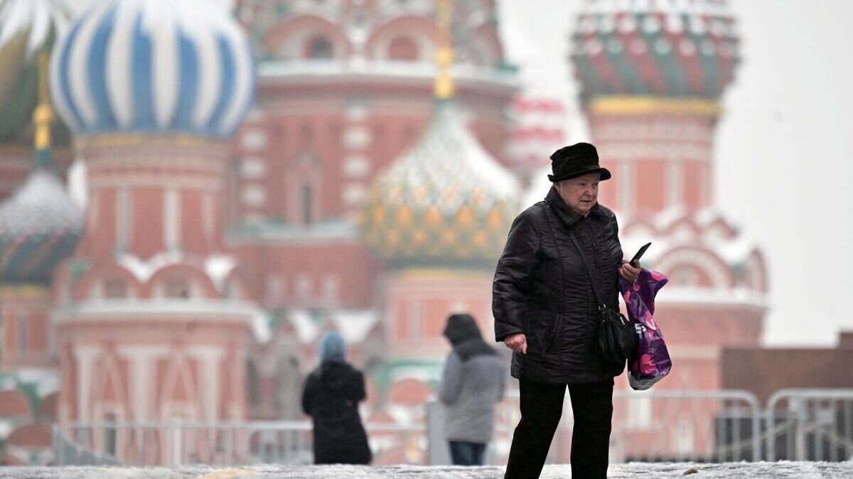    Пожилая женщина на Красной площади во время ледяного дождя в Москве© РИА Новости / Илья Питалев