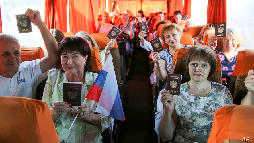Люди, путешествующие в Россию, показывают свои российские паспорта на автобусной остановке в Донецке, Восточная Украина, 27 июня 2020 года.