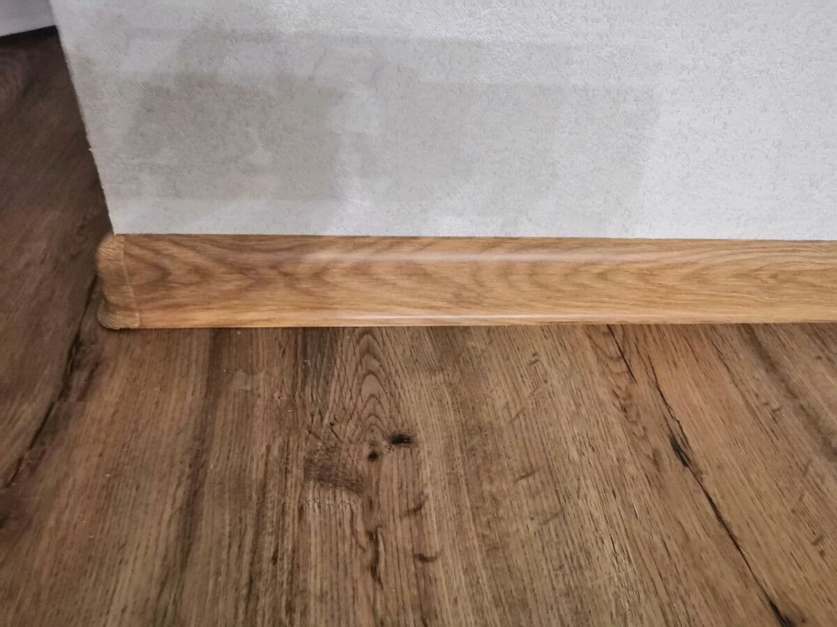 так выглядит кварцвинил на стыке с простым плинтусом.1 кв метр стоит около 1500 рублей: зависит от типа скрепления,цвета и производителя