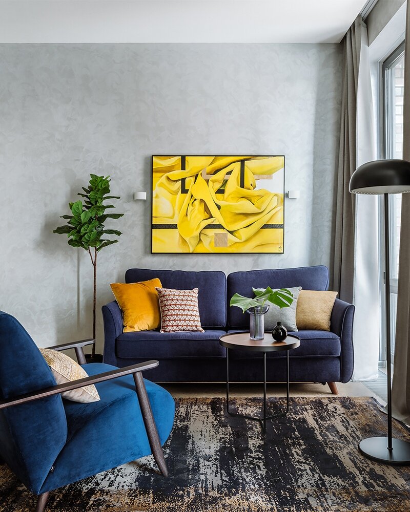 Минималистичный интерьер украшен предметами мебели в стиле mid-century, что делает его более изящным и уютным. А яркие синие цвета в сочетании с яркими желтыми акцентами придают ему особое очарование.