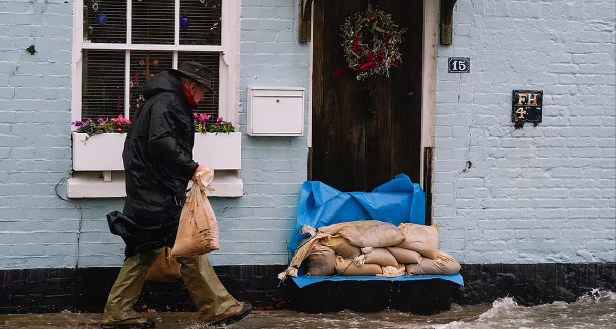 Человек кладет мешки с песком возле дома в Лэнгстоне.