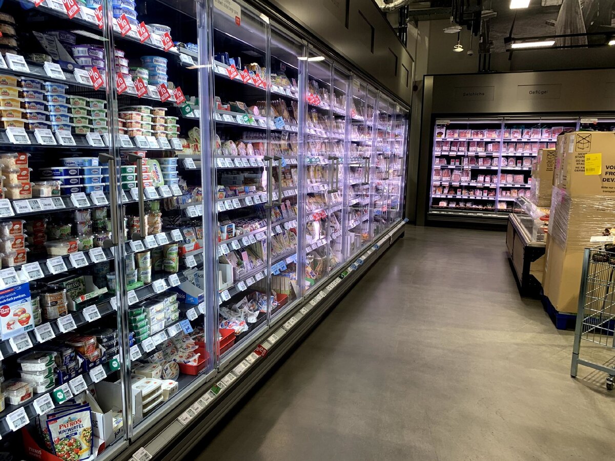 Фото сделано автором в рамках Ритейл Лайт Тура, 21.02.2020г. Продуктовый супермаркет REWE, Friedensallee 9, 22765 Hamburg, Германия. Освещение в холодильных горках выполнено светильниками InteGrade от компании Philips Lighting со специальным спектром. Мы можем это видеть на фотографии: левая часть, где размещена молочная продукция имеет освещение выполненное в нейтрально белом свете 4000К, а правая часть с колбасными изделиями окрашена розовыми тонами