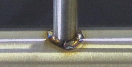 Необработанный сварочный узел с цветами побежалости на нержавеющей стали после сварки 