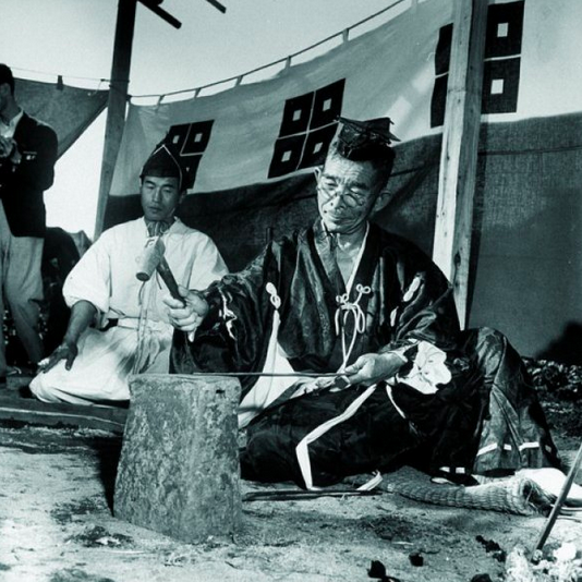 Мастер-оружейник обрабатывает клинок будущей катаны в присутствии синтоистского монаха. К процессу создания самурайского меча в в Японии всегда относились как к религиозному культу. Фото 1950-х годов.