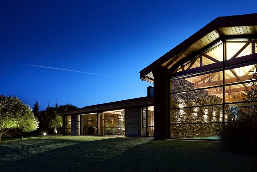 При создании этого дома под Екатеринбургом архитектор Дмитрий Позаренко апеллировал к местным традициям. Вдохновением послужили старинные амбары. Чтобы добиться ощущения подлинности, аутентичности, стены снаружи и частично внутри здания отделали местным башкирским сланцем. Архитектор специально ездил на месторождение и выбирал разные по размеру фракции. А скрепляющий раствор закладывали на глубину, чтобы кладка выглядела предельно достоверно. Фото: Михаил Поморцев.