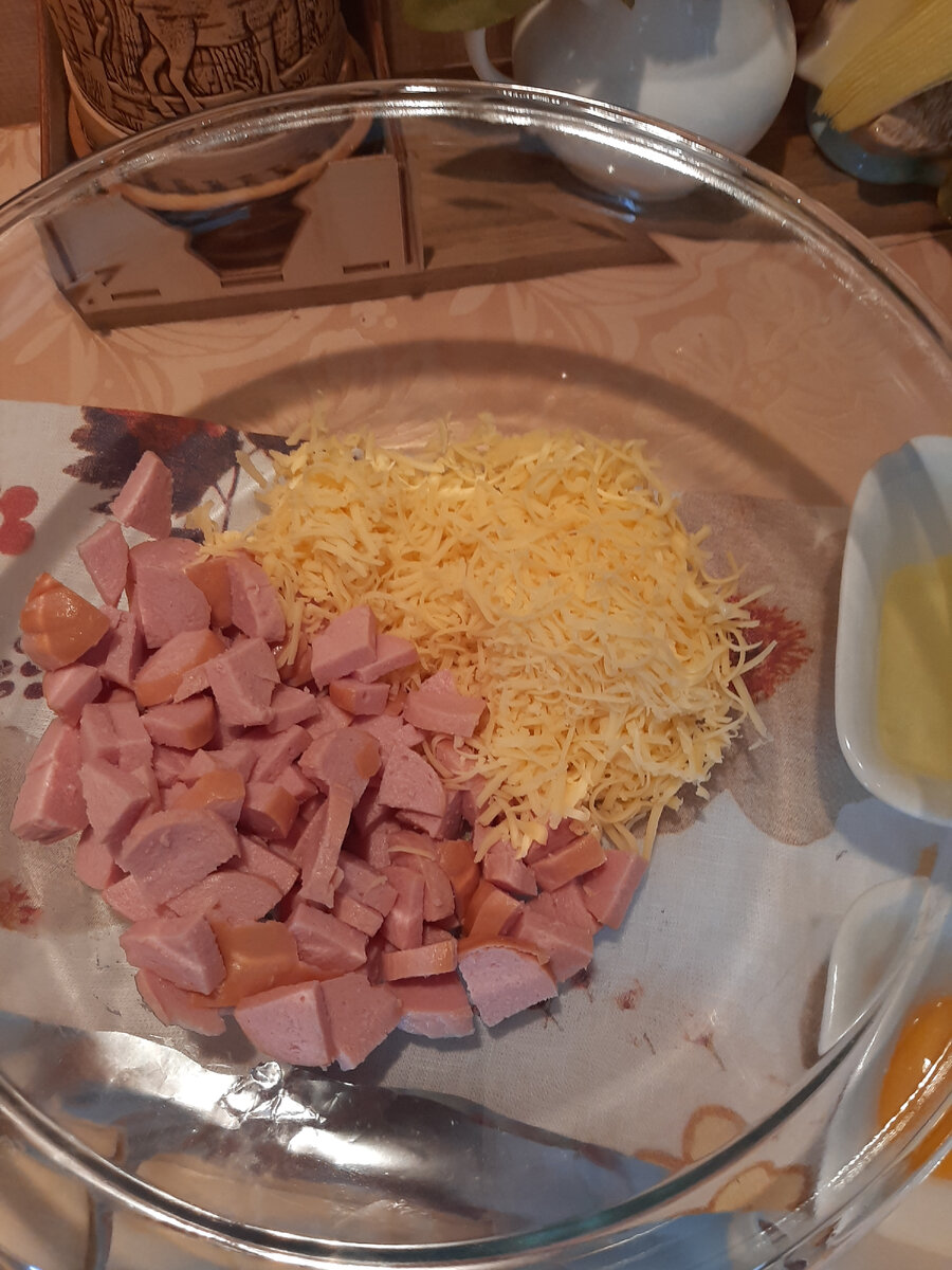 Сардельки порезала средним кубиком, сыр натерла на мелкой терке, белок отделила от желтка.