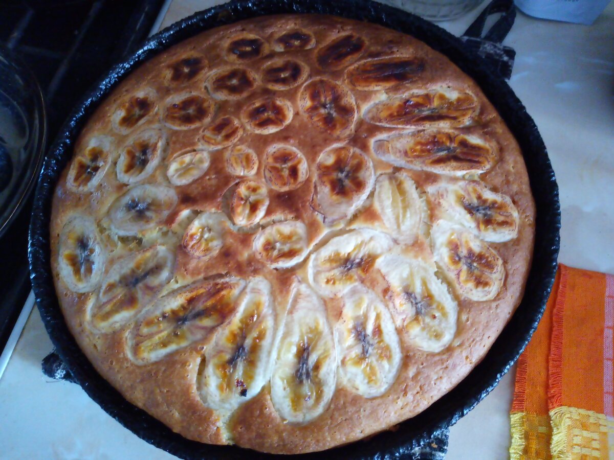 Сладкий заливной пирог с начинкой из сухофруктов, сверху украшен кусочками банана