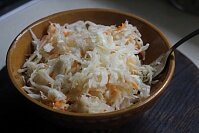 Для начала нужно нашинковать капусту соломкой. Размять белокочанную капусту руками, чтобы она стала мягче. Натереть крупно морковку и смешать овощи. Поместить овощной микс в глубокую тарелку.