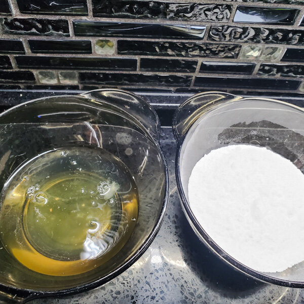 Соединить в чашке белки и сахарную пудру и прогреть на водяной бане до 55 градусов. 