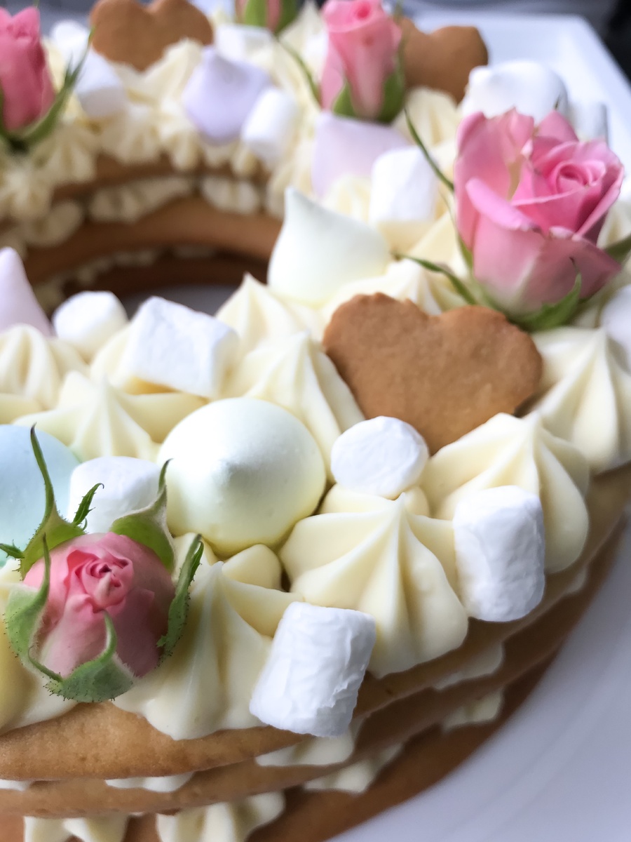 Мягкий нежнейший бисквит, ганаш из белого шоколада украшенный воздушным безе и маршмеллоу , мммм - попробуйте сами😍 
⠀ 
Бисквит:
⠀ Яйца - 2 шт.
⠀ Сахар - 150 гр.
⠀ Мука - 400 гр.
⠀ Сливочное масло - 90 гр.
⠀ Мёд (жидкий) - 70 гр 
⠀ Сода - 1 ч. л.
⠀ Щепотка соли
⠀ 
Ганаш из белого шоколада:
⠀ Шоколад (кондитерский) - 140 гр.
⠀ Творожный сыр - 300 гр.
⠀ Сливки 33% - 100 мл:
⠀ 
⠀ 1. В микроволновке нагрейте сливки примерно 70 градусов, добавьте шоколад и перемешайте до однородности. Накройте пищевой плёнкой и уберите в холодильник на несколько часов.
⠀ 2. Готовим коржи. В кастрюле с толстым дном смешайте до однородности яйца, сахар, мёд, добавьте щепотку соли.
⠀ 3. Ставим кастрюлю на средний огонь, добавляем сливочное масло и нагреваем до полного растворения масла. Смесь должна получиться однородной консистенции.
⠀ 4. Снимаем нашу смесь с огня, добавляем соду, перемешиваем. Даём остыть до комнатной температуры.
⠀ 5. Далее, добавляем муку. Примерно 300 грамм, перемешайте, остальные 100 гр. высыпаем  на рабочую поверхность и замешиваем тесто.
⠀ 6. Чтобы в дальнейшем было проще работать с тестом, уберём его в холодильник на час. 
⠀ 7. Достаем тесто из холодильника, делим на 3 равные части и раскатываем тонким слоем, примерно 0,5 см. Тесто раскатываем сразу на пергаменте. Вы можете придать любую форму вашему торту, сердце, круг, квадрат и т.д. Для этого, просто вырежьте из бумаги трафарет нужной формы)
⠀ 8. Из остатков теста вырезаем украшения на торт, у меня сердечки.
⠀ 9. Отправляем коржи в духовку при температуре 170 градусов примерно на 7-10 минут до золотистого цвета. Коржи должны быть мягкие.
⠀ 10. Пока коржи остывают приготовим крем. К массе из сливок и шоколада добавляем творожный сыр и взбиваем до однородности при помощи миксера.
⠀ 11. Перекладываем ганаш в кондитерский мешок с насадкой и отсаживаем на коржи.
⠀ 12. Сверху украшаем торт нашими фигурными печеньками, маршмеллоу, безе, или по желанию )