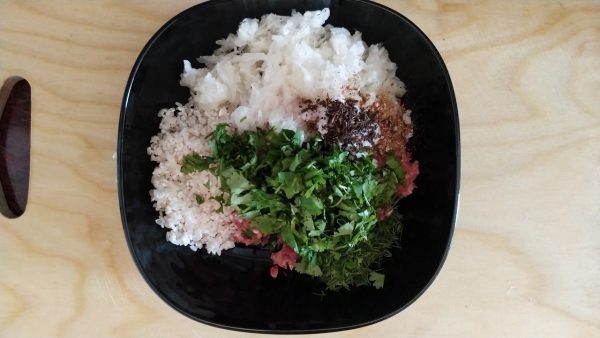 Пропускаем через мясорубку 200 гр телятины (вместо телятины можно использовать говядину), 200 гр баранины и 100 гр бараньего курдючного сала, помещаем фарш в миску. К фаршу добавляем 2 шт измельчённого лука, несколько раз промытый крахмалистый круглозёрный рис, рубленную зелень, зелень добавляйте по своему вкусу, укроп, петрушка, кинза, базилик. добавляем 1 ч.л молотой зиры, соль по вкусу, 3 ст.л растительного масло и всё тщательно перемешиваем.