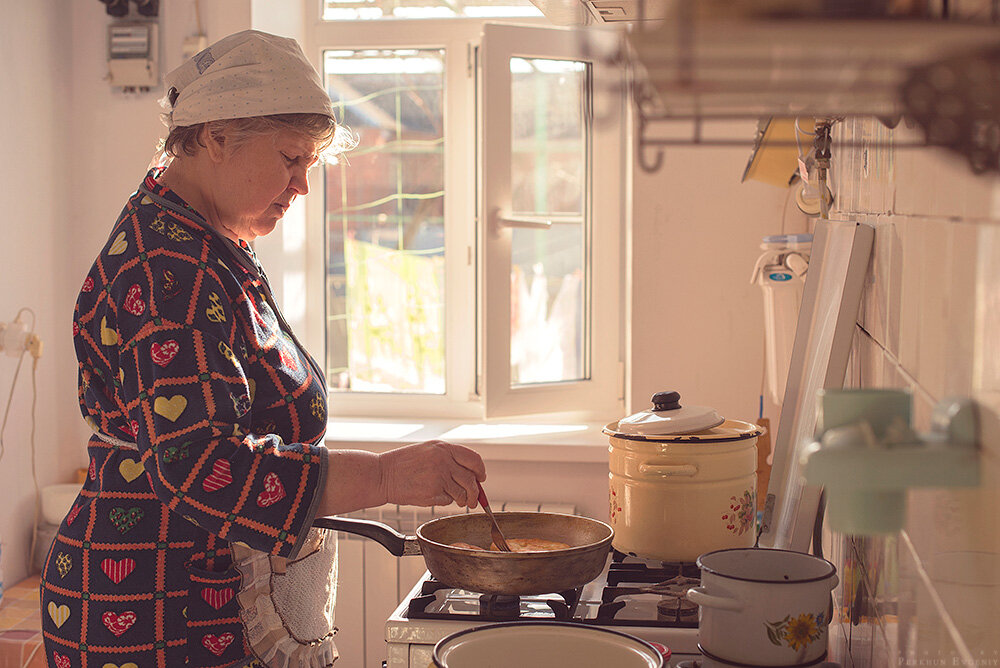 Мама готовит блины. Бабушка готовит. Бабушка на кухне. Старушка у плиты. Пенсионерка на кухне.