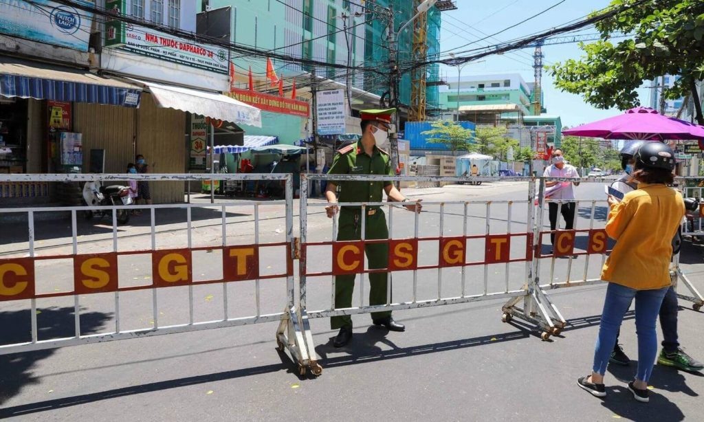 Полицейский в Дананге устанавливает барьеры, чтобы изолировать районы вокруг больниц, где были обнаружены случаи Covid-19
