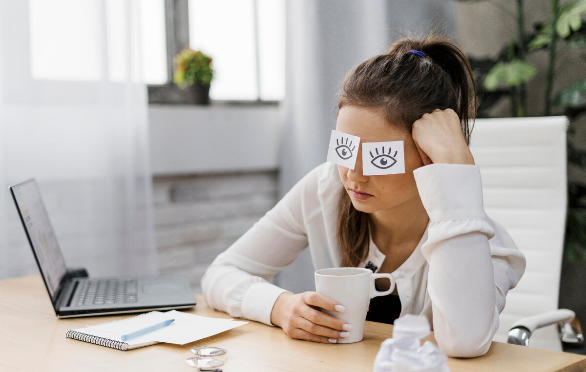 Девушке скучно на работе. Изображение от <a href="https://ru.freepik.com/free-photo/businesswoman-covering-her-eyes-with-drawn-eyes-on-paper_11905106.htm#page=2&query=%D0%BD%D0%B5%20%D1%85%D0%BE%D1%87%D1%83%20%D1%80%D0%B0%D0%B1%D0%BE%D1%82%D0%B0%D1%82%D1%8C&position=0&from_view=search&track=ais">Freepik</a>
