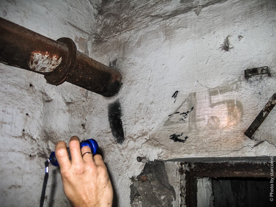 В одном из правофланговых казематов рассматриваем чудом уцелевшее железо, до которого еще не дошли руки мародеров. На штукатурке стены сохранился оригинальный номер каземата