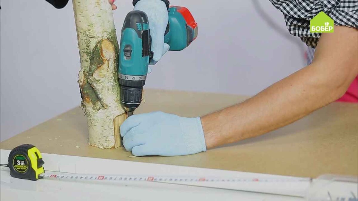 При помощи железных уголков прикрепите ножки из берёзовых стволов к столешнице .