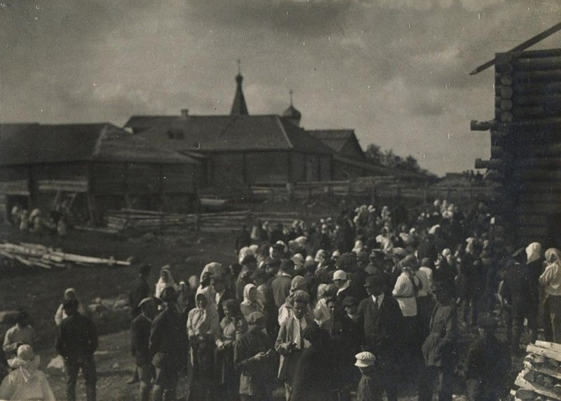 ФОТОГРАФИЯ из альбома Ю.М и Б.М.Соколовых "По следам Рыбникова и Гильфердинга". Праздничное гулянье в Иванов день в селе Леликово. 06.07.1926 г.
В кадре: многочисленная группа мужчин, женщин (встречаются дети), одетых по-летнему. На первом плане – мужчина в белой рубашке с галстуком, светлом костюме, без головного убора (Ю.М. Соколов ?), справа – молодой человек в темной рубашке, без головного убора (С.П. Бородин ?). На втором плане справа – часть бревенчатого строения. Слева на втором плане – бревна на земле, деревянные строения за оградами из жердей, за ними видны часть колокольни и купол культовой постройки, деревья.