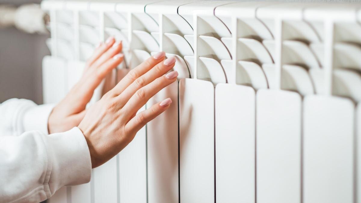    Женщина греет руки у батареи:nikkimeel/Getty Images