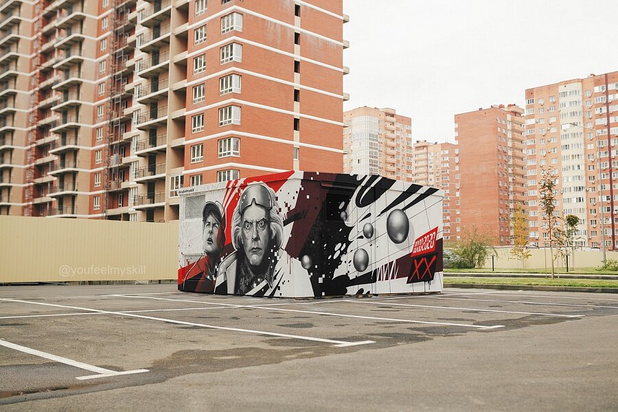 Граффити по мотивам кинотрилогии «Назад в будущее» появилось в ЖК «Перспектива». Оно стало первой краснодарской работой Яна Кузьмина. Мы задали Яну несколько вопросов: ⠀
Ты в первый раз в Краснодаре? Что удалось посмотреть?
⠀
Приезжал после Нового года отдохнуть на неделю, погулять. Рисовал на Затоне просто шрифты, классику для себя. А сейчас в первый раз приехал сюда по работе. После этого проекта буду рисовать еще один коммерческий заказ в одном из ресторанов. Когда закончу, планирую посетить Затон либо какое-то другое легальное место для рисования, чтобы сделать граффити, со шрифтами поработать.
⠀
Какое у тебя впечатление от этого района?
⠀
Мало что успел посмотреть, но порадовало, что в каждом дворе есть спортивная площадка, рядом скейтпарк. Понравилось, что здесь оформляют все трансформаторные подстанции. Видел пару работ – не просто будки стоят, а приглашают ребят их расписывать. В целом, от района хорошее впечатление, потому что в городе, из которого я родом (прим. ред. Витебск), там, где новостройки, все очень грустно и пусто.
⠀
Когда начал рисовать эту тему, какой был отклик от прохожих?
⠀
В первый день, когда рисовал, здесь стоял грузовик и нас не было видно, подошли два человека сфотографироваться. Потом работу выложили в инстаграм. Когда картинка вырисовалась, и люди поняли, что это будет, диалог с прохожими складывался.
⠀
Как бы ты мог охарактеризовать свой стиль?
⠀
Мне тяжело его охарактеризовать, так как сейчас я часто экспериментирую. Сейчас больше ухожу в композицию с портретами, абстрактными паттернами. Я это называю стиль Youfeelmyskill – постоянно узнаваемая цветовая гамма и сочетание с портретами, абстракциями.
Если бы тебе дали пустую стену сейчас, что бы ты нарисовал? О чем мечтаешь?

То, о чем я мечтал, реализовал осенью в Ульяновске. Это фасад 5-этажного здания с композицией – девочка с книгой и граффити шрифтами. С детства, когда я познакомился с граффити, думал, что было бы здорово расписать не просто портреты, а именно классику граффити – шрифты, на заднем плане латинский алфавит. Все зависит от стены, где она находится, какая конфигурация и уже отталкиваться от этого. Я перестал привязывать свое творчество к названию улиц, к датам – этого стало очень много в России, поэтому я максимально стараюсь уйти от этого.
⠀
Какое у тебя сейчас соотношение коммерческих заказов и рисунков «для себя»?

Примерно 60 на 40. Коммерческих проектов чуть больше, но их не афиширую, выкладываю только некоторые на своем сайте. Все, что есть в социальных сетях, – на социальные темы либо моя инициатива для города. К сожалению, мир так устроен, я бы с радостью отказался от большинства коммерческих работ, потому что многие из них как творческая задача не интересны. Они исключительно для заработка, жизни, покупки расходных материалов. Я думаю, любой художник граффити согласится со мной.
⠀
Тебе нравится затрагивать социальные вопросы в своих работах?

Да, но я сейчас ближе к искусству, чем к острому, социальному. Интересно работать на какие-то актуальные темы, но мы все-таки в России живем… с этими вещами нужно быть аккуратнее. Иногда это здорово.
⠀
В какой стране ты бы хотел еще поработать?

Если говорить о масштабных проектах, однозначно в Европе, где-нибудь в Испании. Хотел бы посетить Швецию, Австрию, Германию. Из Азии – Токио, очень продвинутый город, Китай. Австралию бы посетил, возможно, не для творчества, а для общего развития. Ну и, конечно, США – они всегда на 10 шагов впереди во всех направлениях. Было бы интересно посмотреть, как там работают художники.