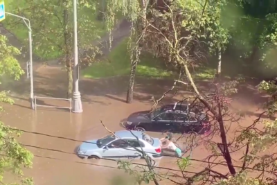    Фрагмент видео, как люди из огромной лужи толкают машину после дождя в Москве ©Скриншот