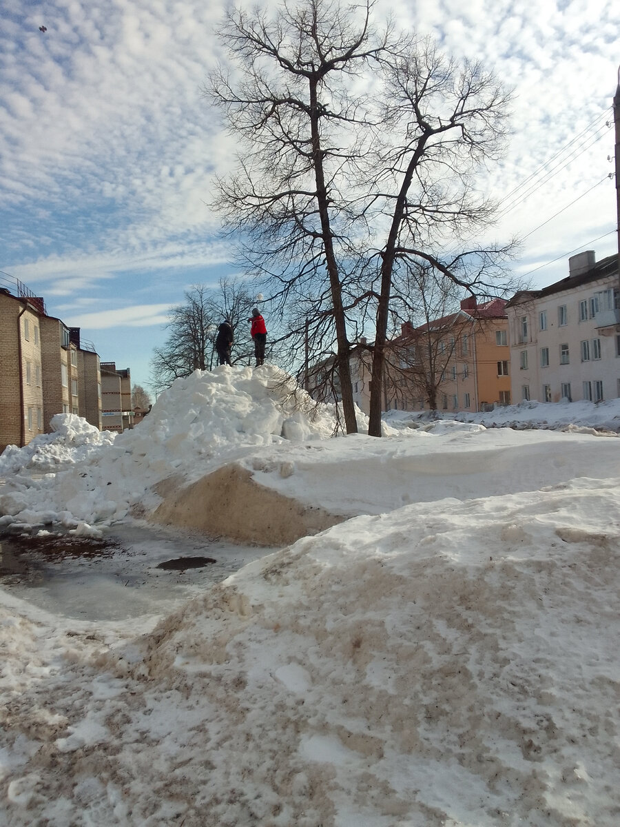 Мальчишки  на большой куче  снега. 