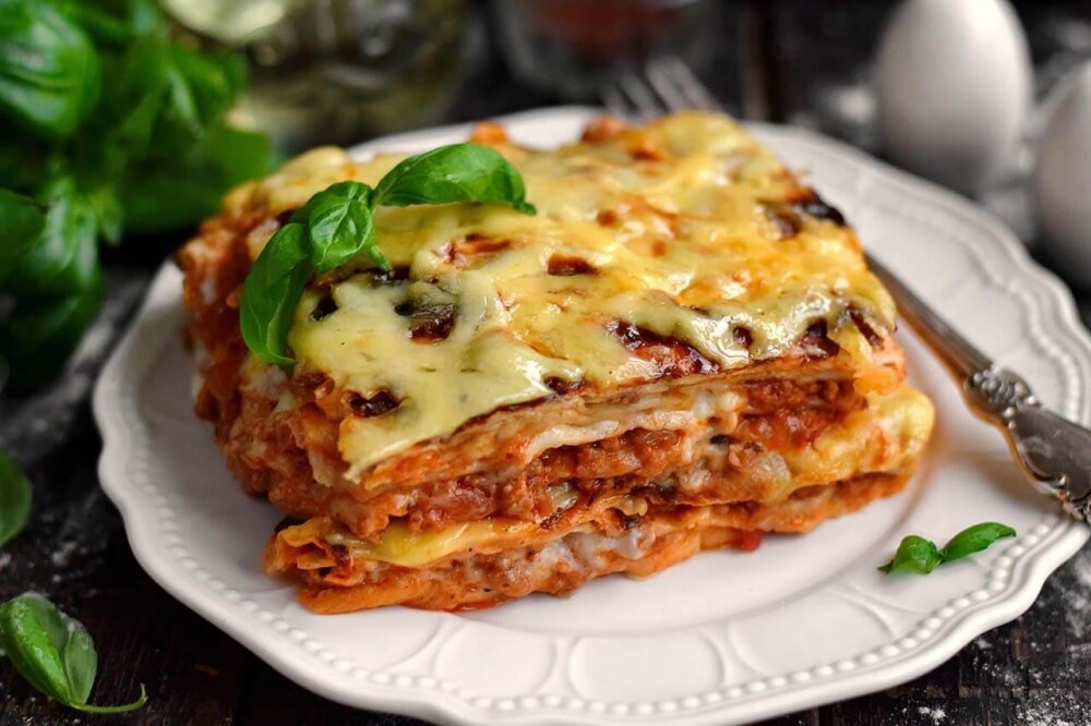 Время приготовления : 60 минут / Порций : 6                                                                           Ингредиенты :                                                                                                                                                              Лаваш тонкий-220 гр
Мясной фарш-500 гр
Лук репчатый-1 шт
Помидоры-1-2 шт
Томатный соус-1-2 ст.л
Сыр твердый 50%-100 гр
Моцарелла-100 гр
Растительное масло для жарки-2 ст.л
Смесь трав- по вкусу
Молоко-400 мл
Мука-1 ст.л
Сливочное масло-1 ст.л
Мускатный орех-1 щепотка
Соль- по вкус 