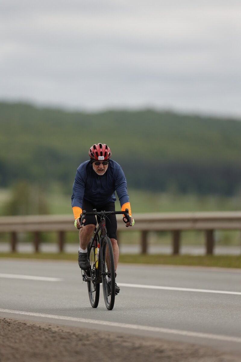 Начало идет в легкий подъем, группа шоссейников-спортсменов уезжает вперед, остальные начинают постепенно растягиваться