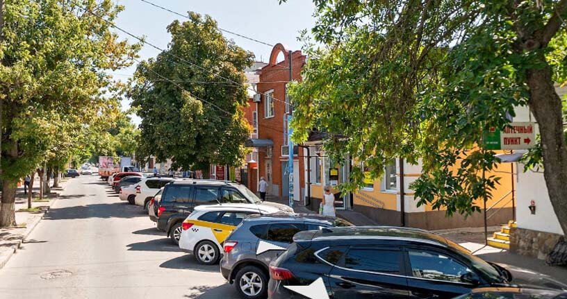 На правой стороне улицы, слегка скрытая деревом красная надпись. (картинка взята на Яндекс-картах)