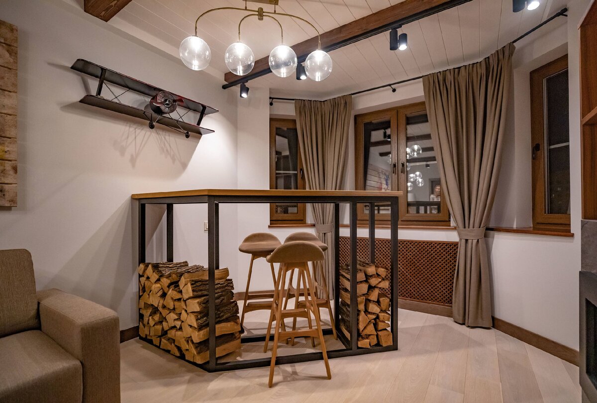 В глубине комнаты разместили барную стойку, оформив зону для отдыха. Ее расположили под тупым углом, обыграв эркер.