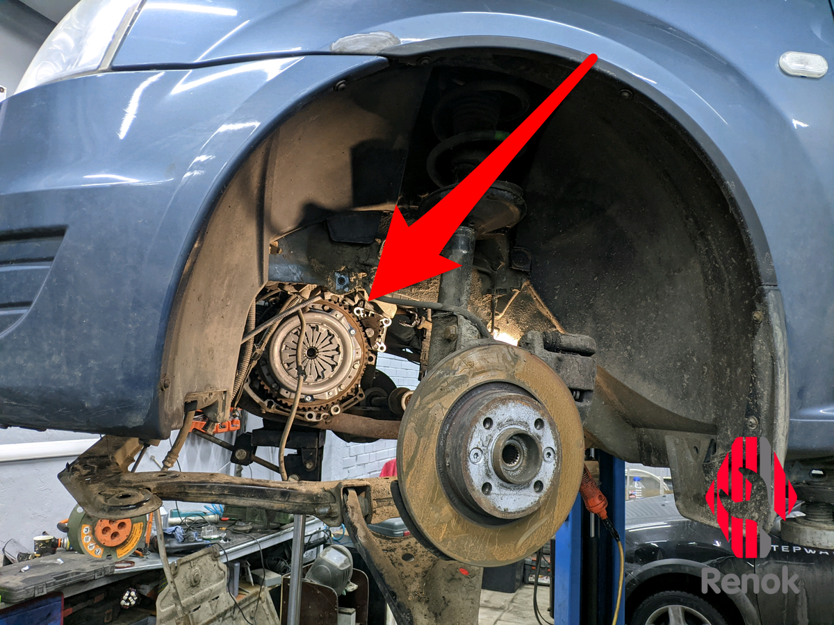 Автомобиль Renault Logan на подъёмнике со снятыми колёсами. Стрелка указывает на установленную корзину сцепления. 