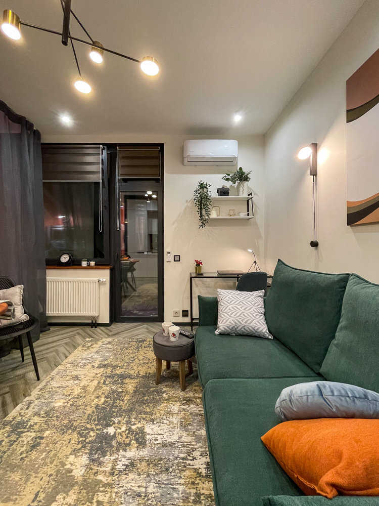 Ближе к окну обустроили рабочее место. Стол-консоль выглядит очень компактным не только за счёт своей небольшой глубины, но и благодаря стеклянной столешнице. А чёрный металлический корпус добавляет интерьеру графичности.
