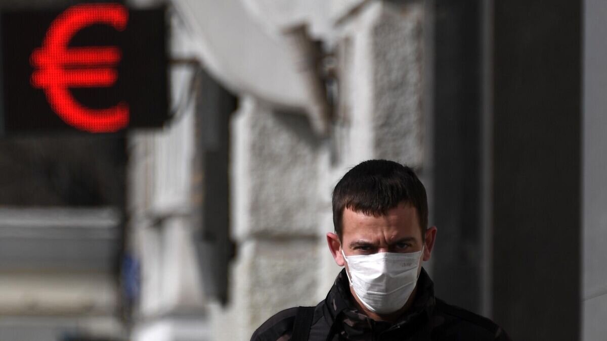    Человек в медицинской маске около электронного символа "евро" в Москве© РИА Новости / Алексей Филиппов