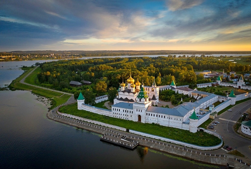 На переднем плане Ипатьевский монастырь в устье реки Костромы, где она впадает в великую Волгу. Волга на заднем плане. Слева видны деревянные домики-это музей деревянного зодчества Костромская слобода-он рядом с Ипатьевским монастырём.У стен Ипатия причал, где причаливают прогулочные теплоходы. Справа за кадром мост через реку Кострому.