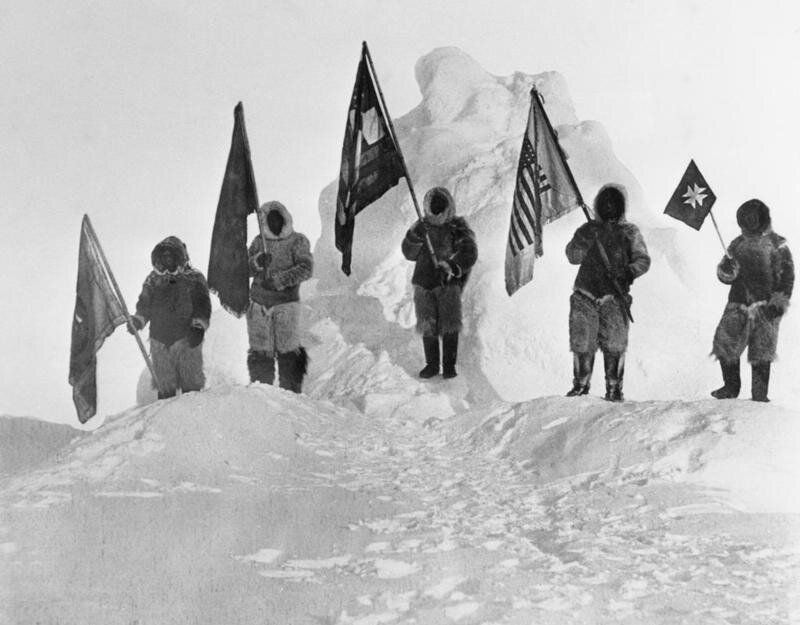 1909: Первооткрыватели Роберта Пири, одетые в меха и держащие флаги на Северном полюсе. 
