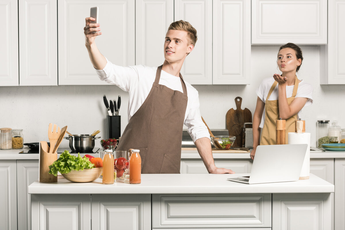 Фото с сайта https://ru.depositphotos.com/category/business-finance.html Парень делает селфи со смартфоном на кухне
