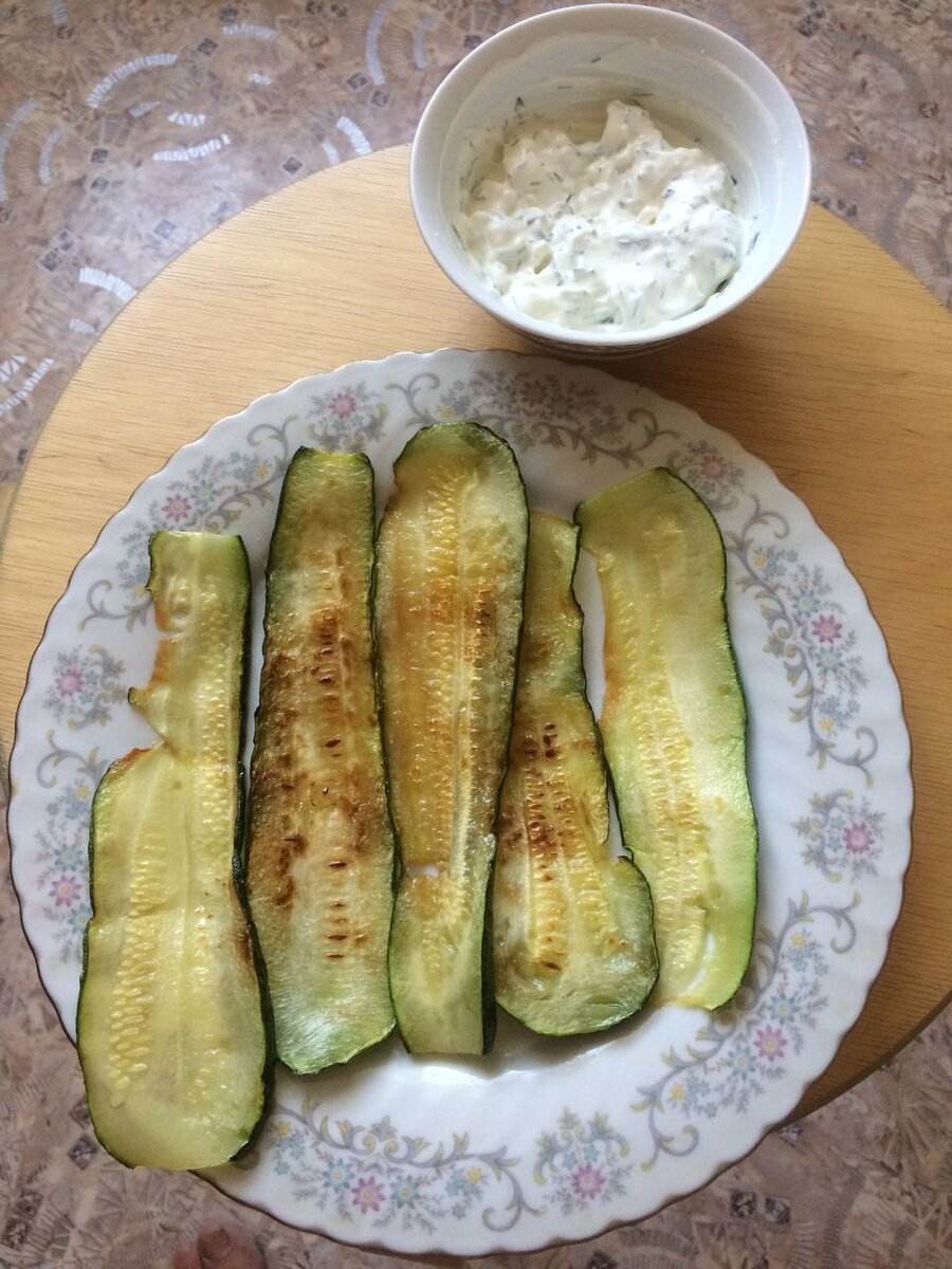 Промываем кабачок, нарезаем тонкими слайсами и обжариваем с двух сторон до золотистого цвета. Готовим соус- выдавливаем чеснок в творожный сыр и смешиваем с измельченной зеленью. Солим по вкусу. 