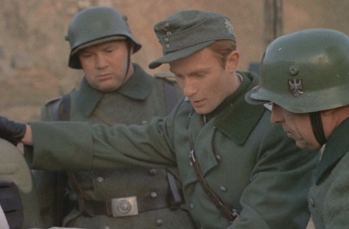 Немецкие солдаты в касках с "рогами". Под касками кепи. Кадр из фильма