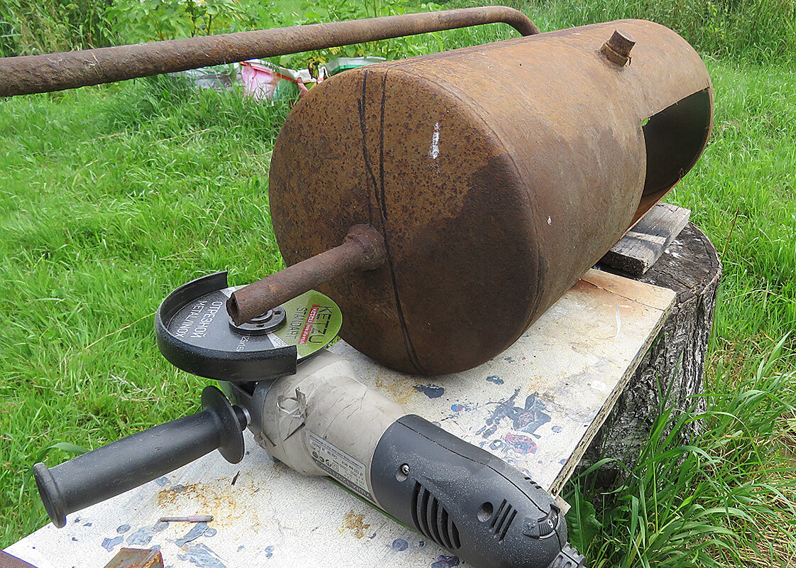 Старый баллон установлен на пенек перед домом.