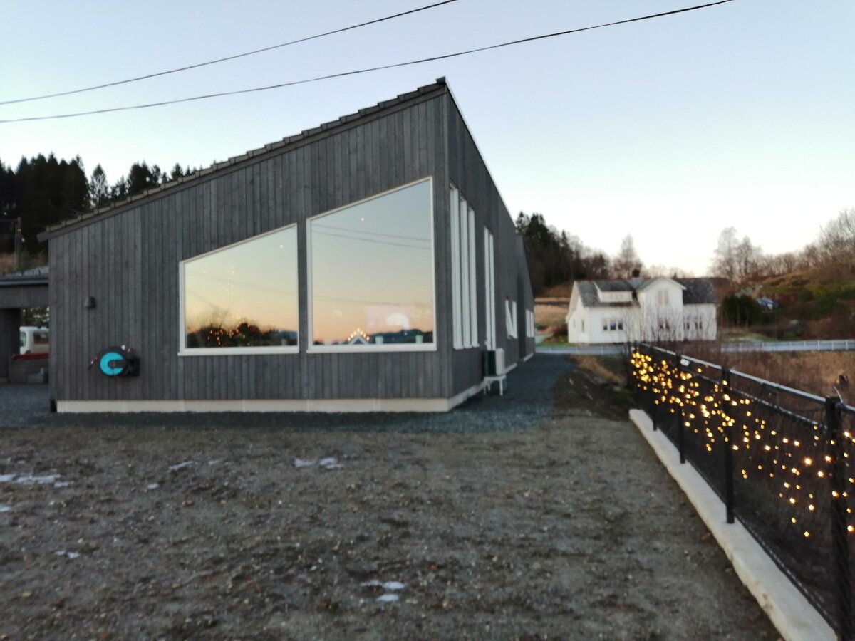 Дом Александра в стиле скандинавского модерна.Виден старый фермерский дом по другую сторону дороги. На снимке он белого цвета.