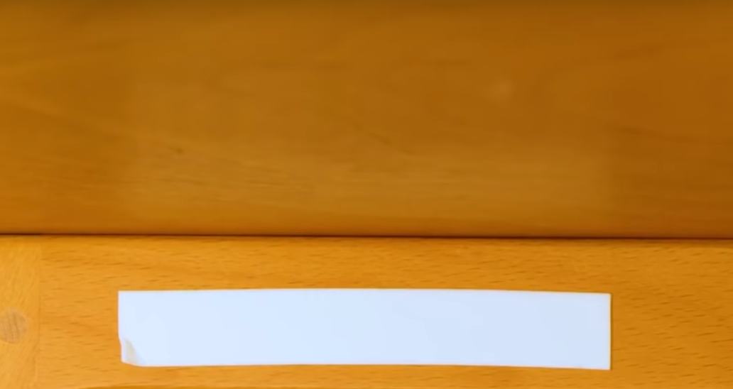 Отрываем небольшой кусочек двустороннего скотча и клеим его к столу перед диваном