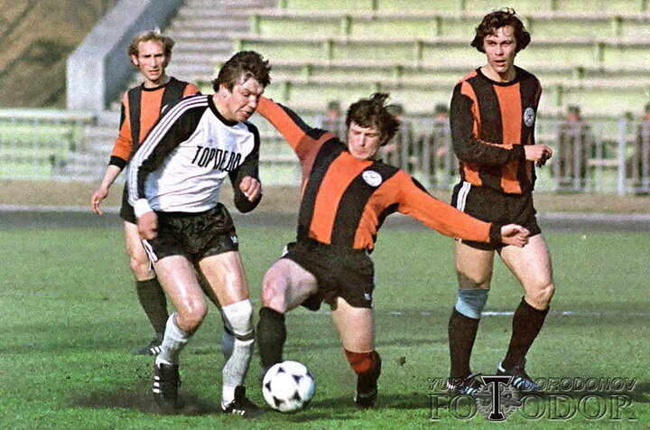 Владимир Пьяных (1970-71, 1974-83)
После дебюта в основе «Шахтера» в 19 лет Пьяных (на фото – в центре, идет в подкат) отправили крепнуть в состав одноименного фарм-клуба из Кадиевки. Затем игрок и вовсе попал в «армию», играя за черниговский СКА и едва не попал в московский ЦСКА, но оттуда его отпустили. Там Пьяных дембельнулся, а «Шахтер» получил крепкого центрбека, на годы занявшегося место в основе. Пьяных не часто ходил вперед, потому его первый гол – тбилисскому «Динамо» в финале Кубка СССР-1980 – произвел эффект разорвавшейся бомбы. По воспоминаниям самого игрока, его тогда едва не задушили свои же партнеры прямо на поле. Пьяных играл предельно жестко, но знал грань фола, потому неудивительно, что после окончания карьеры стал успешным футбольным судьей.
