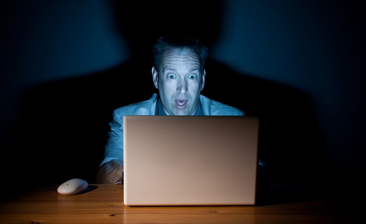 Человек сидит за компьютером. Лицо смотрит в экран. Человек на экране. Лицо смотрит в экран. Лицо смотрит в экран.