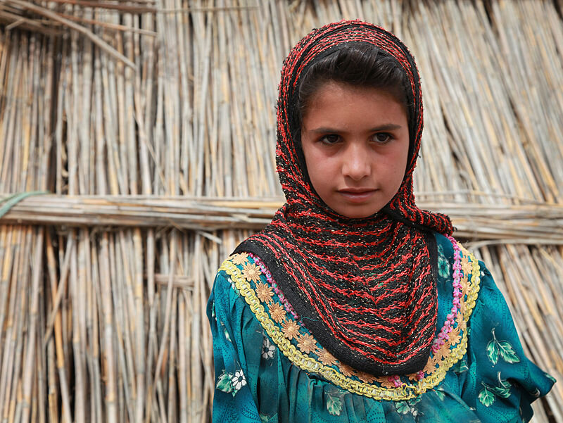 Арабская девочка на фоне хижины из камышей.